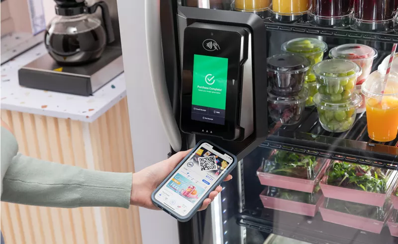 Women scanning 365 mobile app on payment terminal of vending machine